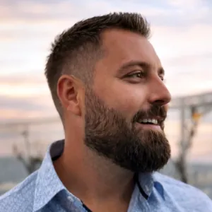 Mann smiler til venstre med blå skjorte